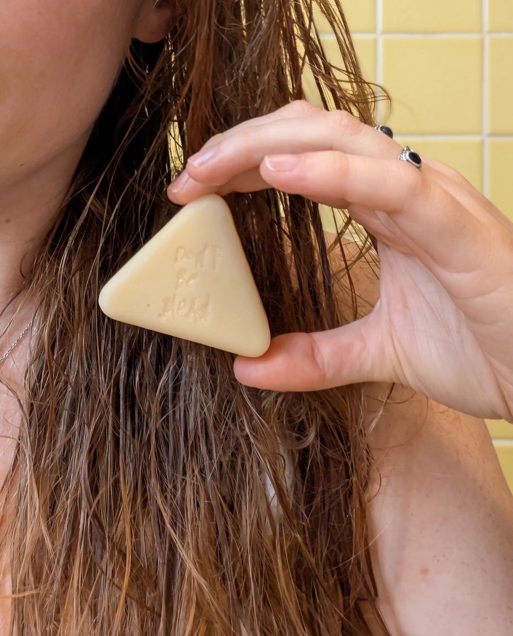 Hand gliding a solid conditioner bar down the lengths of wet hair