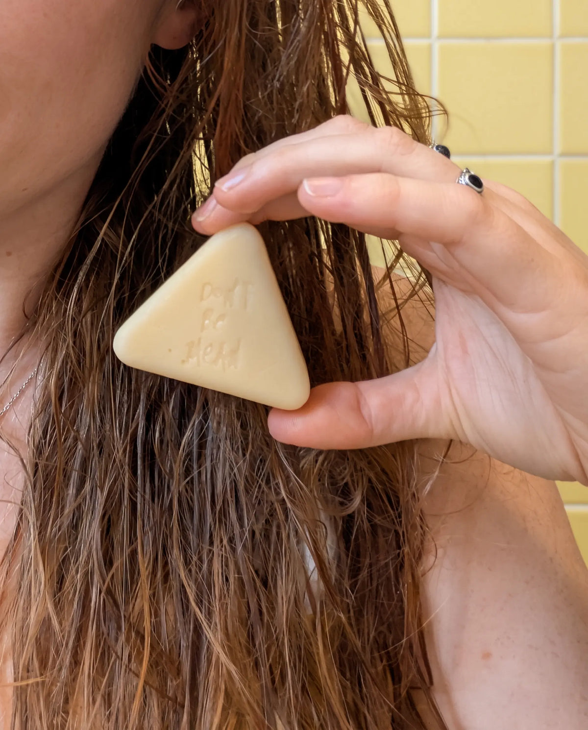 Hand gliding a solid conditioner bar down the lengths of wet hair